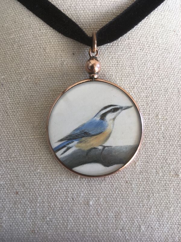 Nuthatch. In a round locket on a velvet ribbon