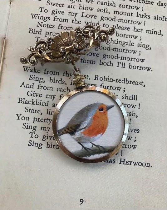 Robin redbreast. A vintage locket hung from an antique brooch
