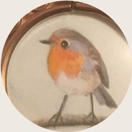 Close-up of a painted robin on a round cream disc